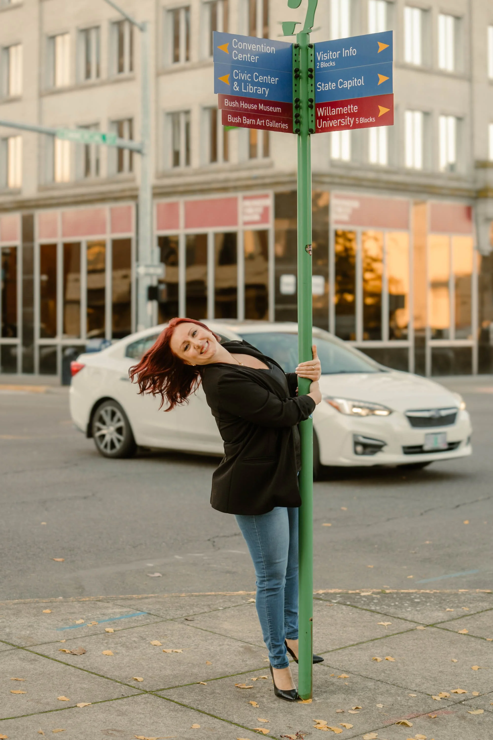 Havenrose Real Estate relocation specialist Katy Voves  playfully posing at a Salem, Oregon downtown directional sign near State Capitol and Willamette University