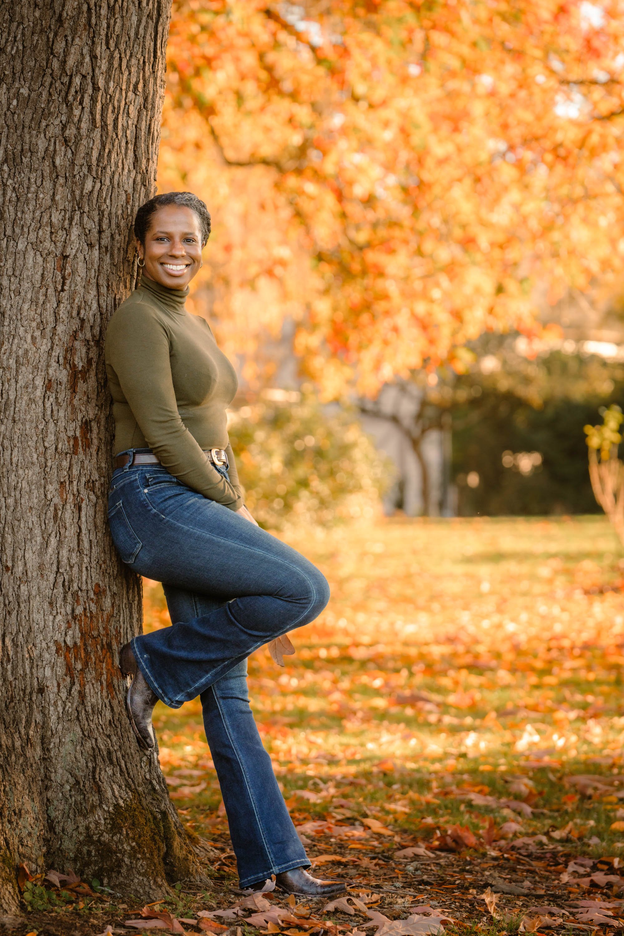 Havenrose Real Estate broker Allie Saunders  leaning against a tree in a Salem, Oregon park surrounded by brilliant autumn color