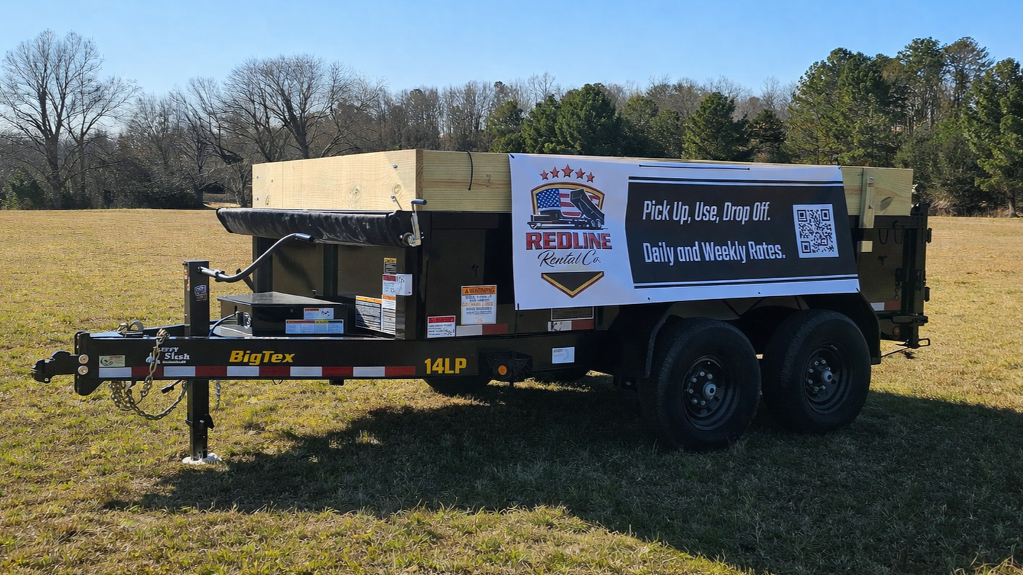A black utility trailer with a wood plank bed parked on grass, featuring a large banner advertising a rental company, with the company logo, contact information, and QR code, in a rural outdoor setting.