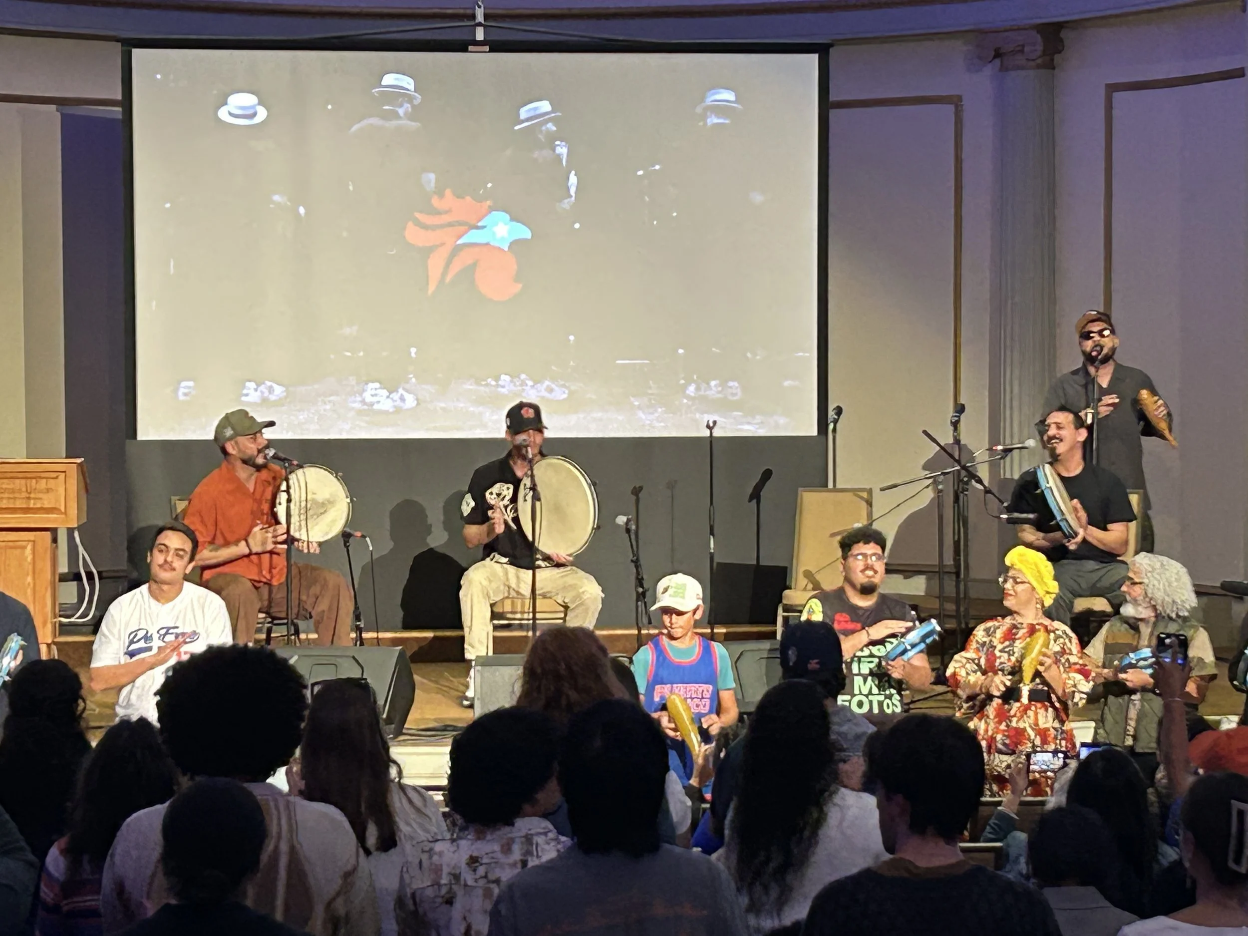 Band performing on stage, smiling and playing in front of a crowd.