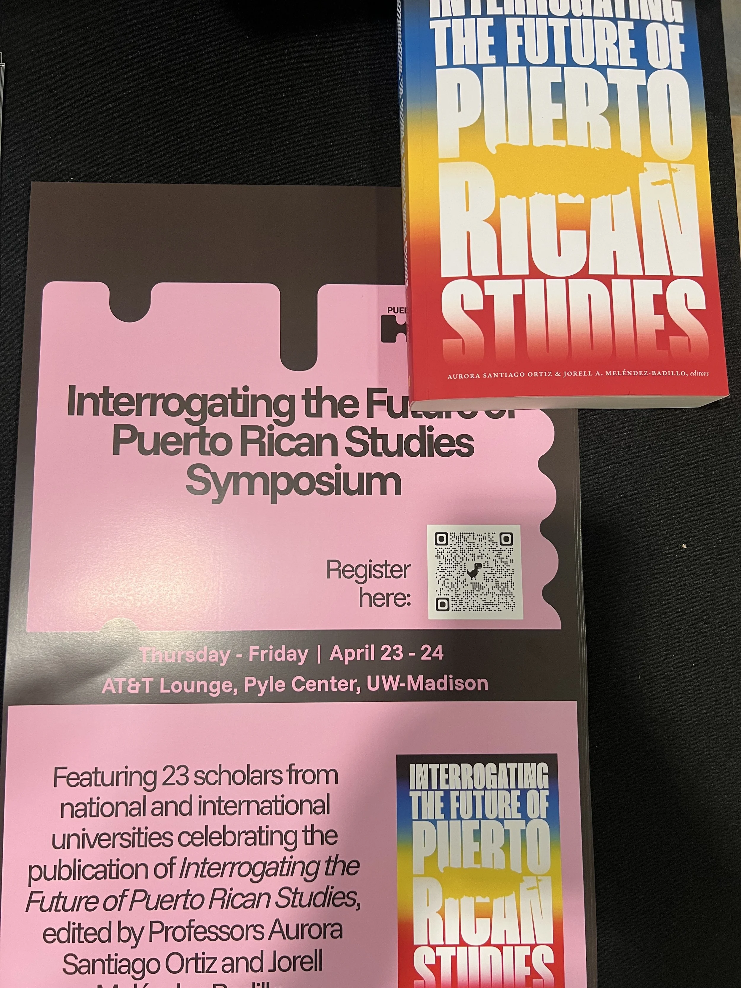 A black and pink flyer with the Hub’s branding and a colorful book cover promoting the Interrogating the Future of Puerto Rican Studies Symposium. 