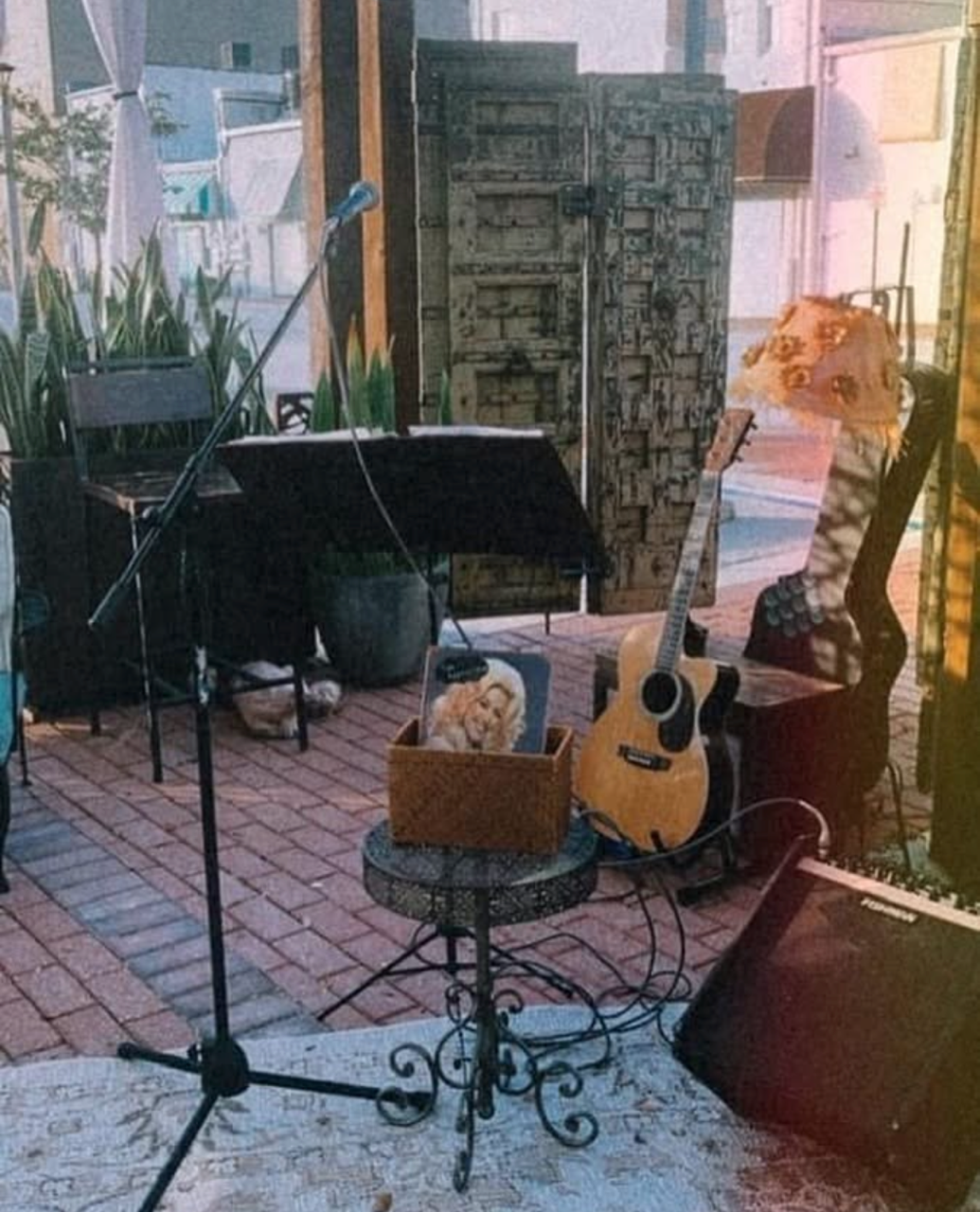 A cozy outdoor music setup with a microphone, guitar, and amplifier. Live music at Hatfield's Hideaway