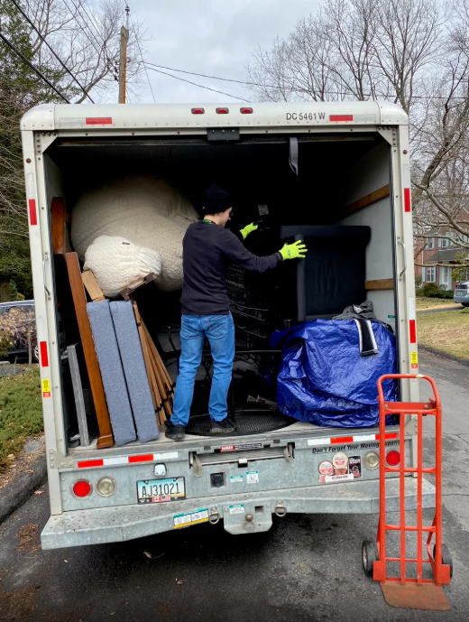 Person inside a moving truck loading or unloading furniture and boxes during daytime.