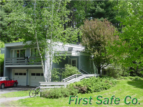 House with a driveway, red car, bicycle, surrounded by trees and grass, with 'First Safe Co' text at the bottom.