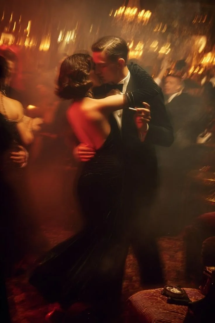 A couple dancing closely at a formal party or ballroom, with dim lighting and other guests in the background.