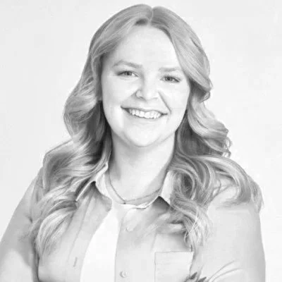 Black and white photo of a woman with long, wavy hair smiling at the camera.