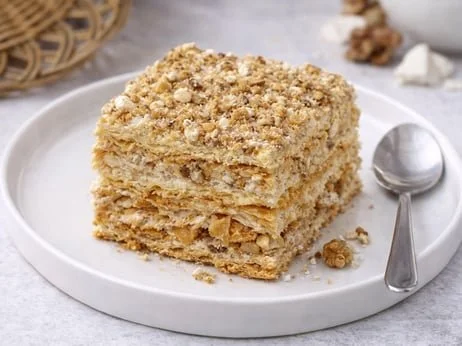 Layered pastry cake with cream filling and crushed nuts.