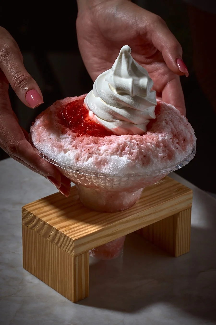	
Hands holding the Strawberry Shaved Ice dessert at Matcha Cafe Maiko.