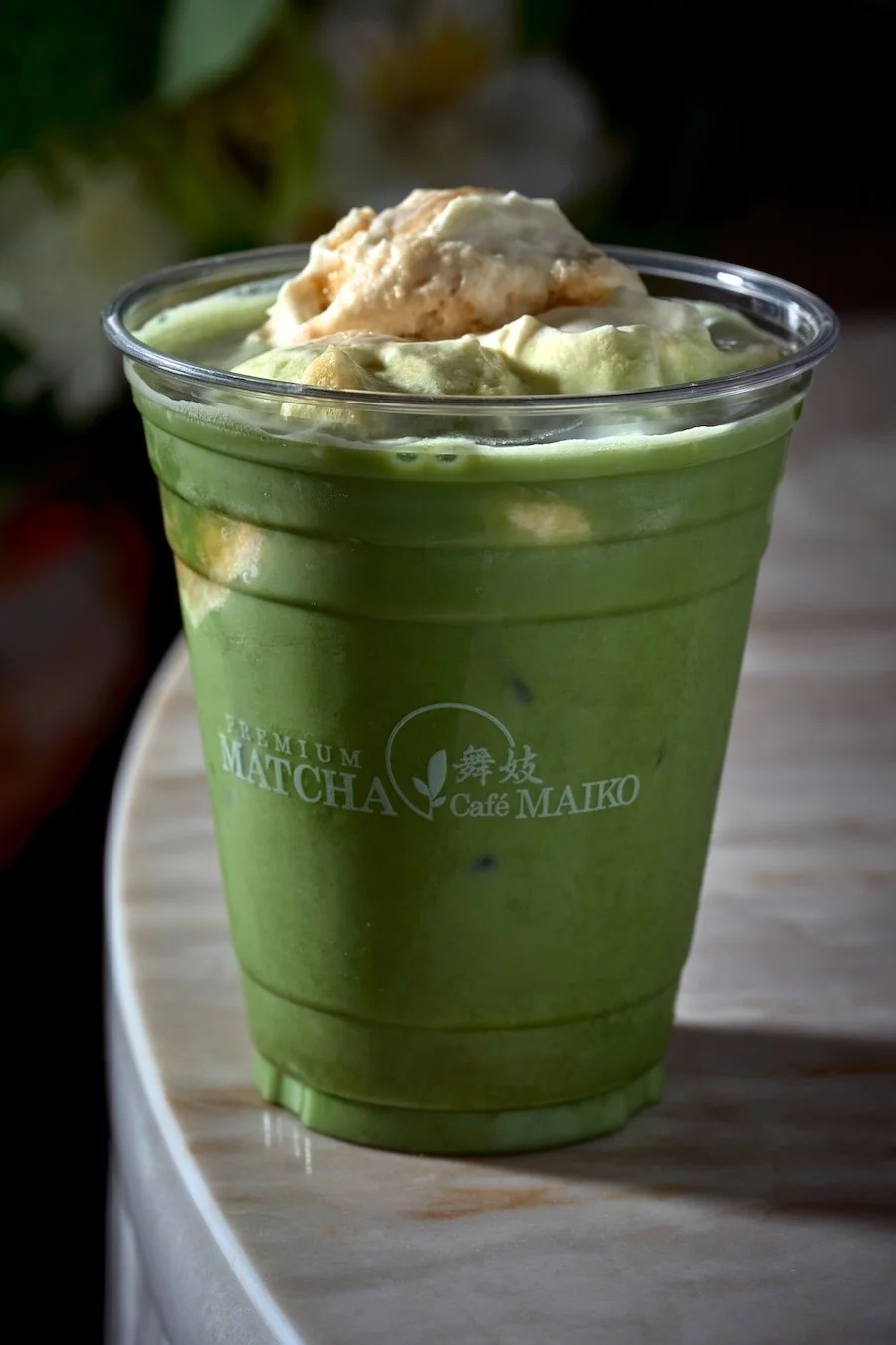 A cup of a Matcha Cafe Maiko Banana pudding Matcha latte.