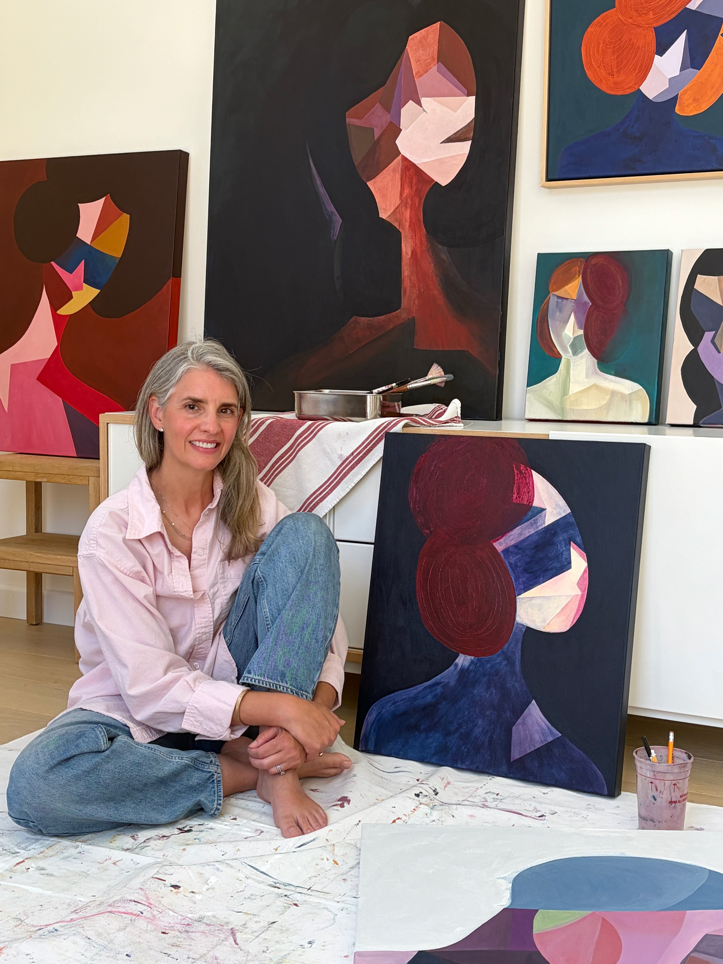 Rebecca Brey seated in her Los Angeles studio surrounded by paintings from the Masked Fragments series
