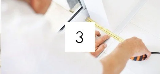 Person measuring and marking something on a piece of paper with a tape measure.