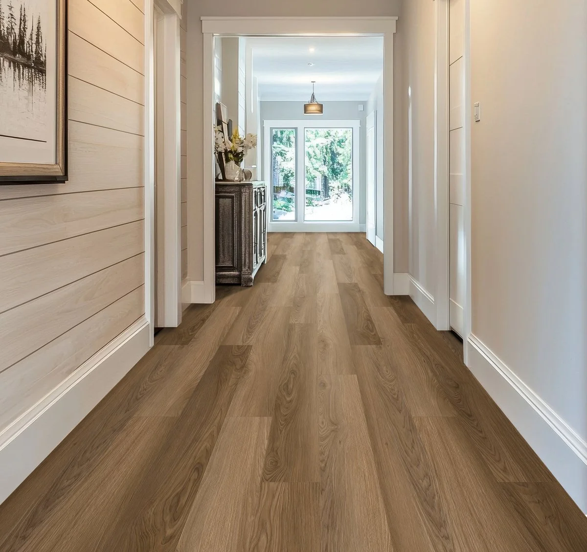 Bright hallway with wood flooring, white walls, and a view of a glass door leading outside with greenery visible.