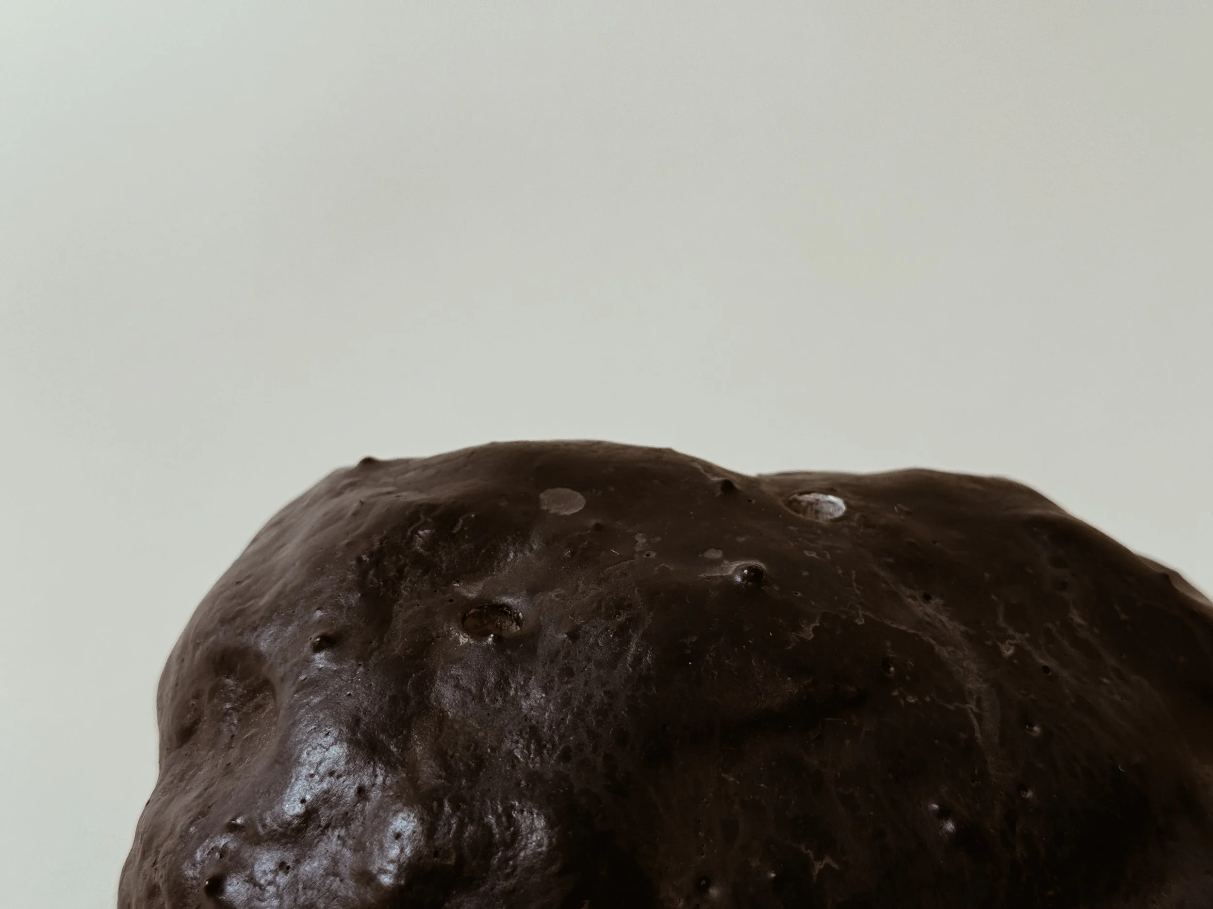 Extreme close detail of midnight Specimen Display Rock by Kept LA  showing proprietary ceramic-like glaze surface texture with deep  black pigment and subtle variation in finish