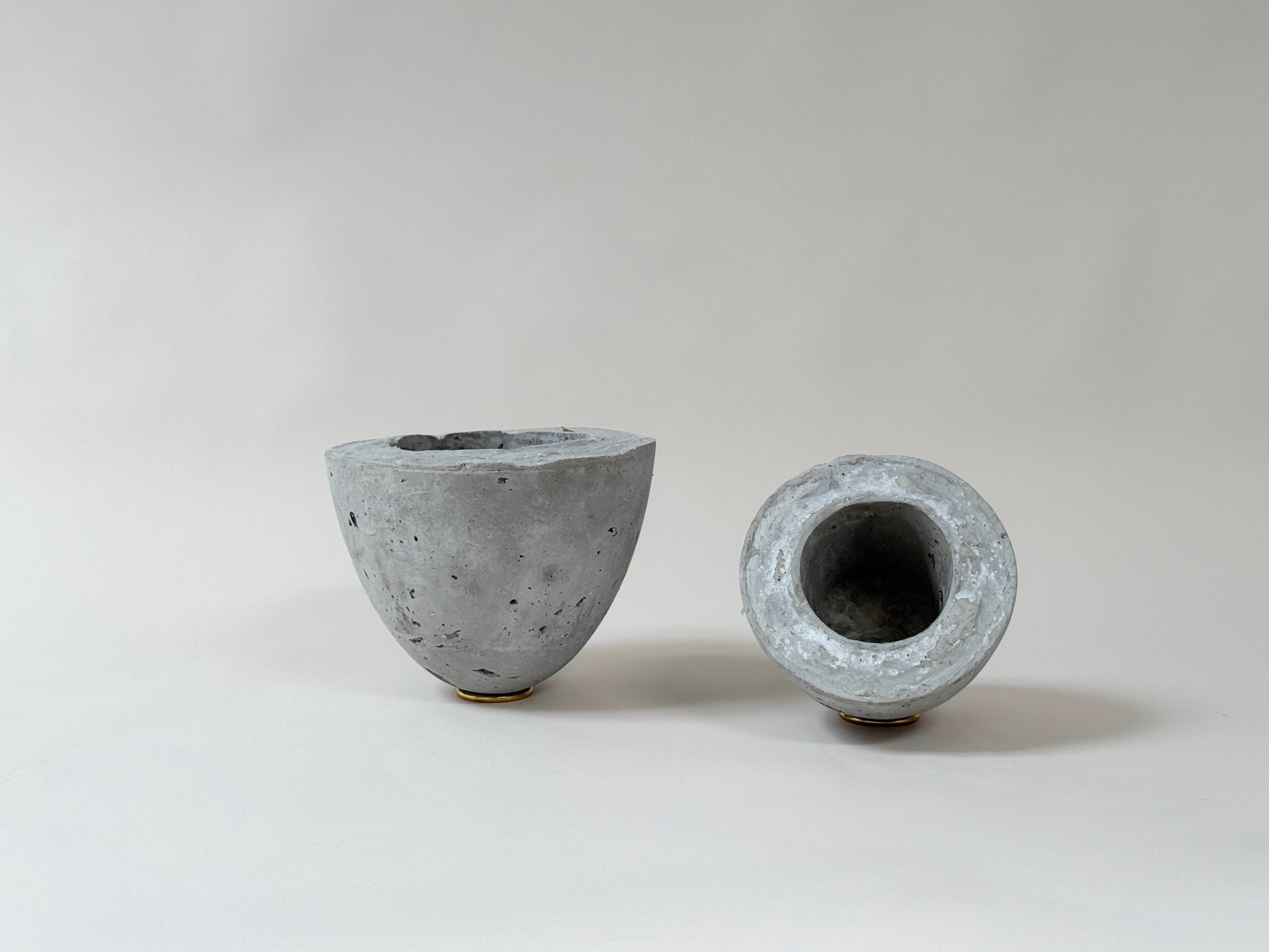 Two Vaultic concrete vessels by Kept LA — one upright showing  interior cavity, one inverted showing domed exterior form