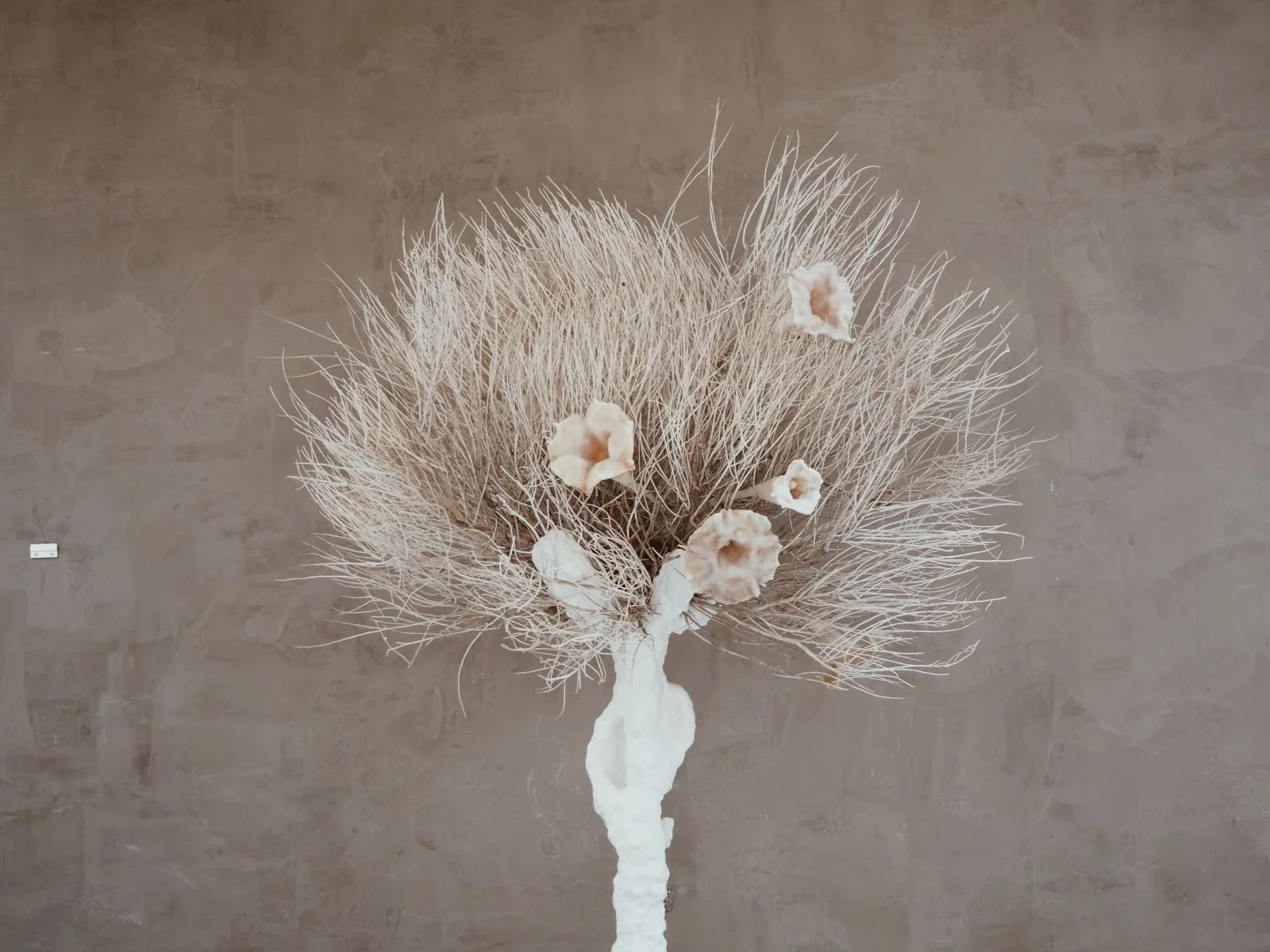 Sagebrush Totem by Kept LA mid view focusing on natural sagebrush  canopy with wax brugmansia flower embellishments nestled throughout,  plaster-finished base visible below