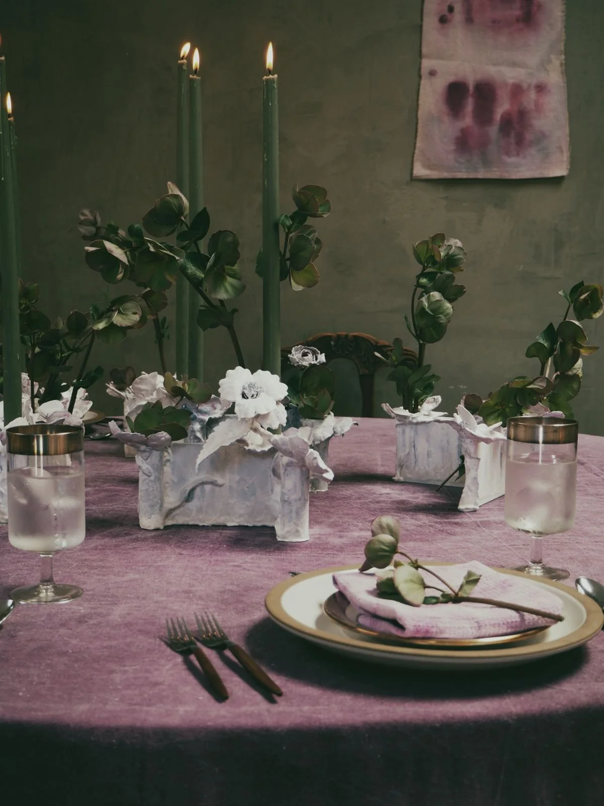 Full editorial dining table with lit sage taper candles, hand-cast tole gypsum vessels, hellebore botanicals and custom hand-painted purple linen — Kept LA artisanal event tabletop design Los Angeles