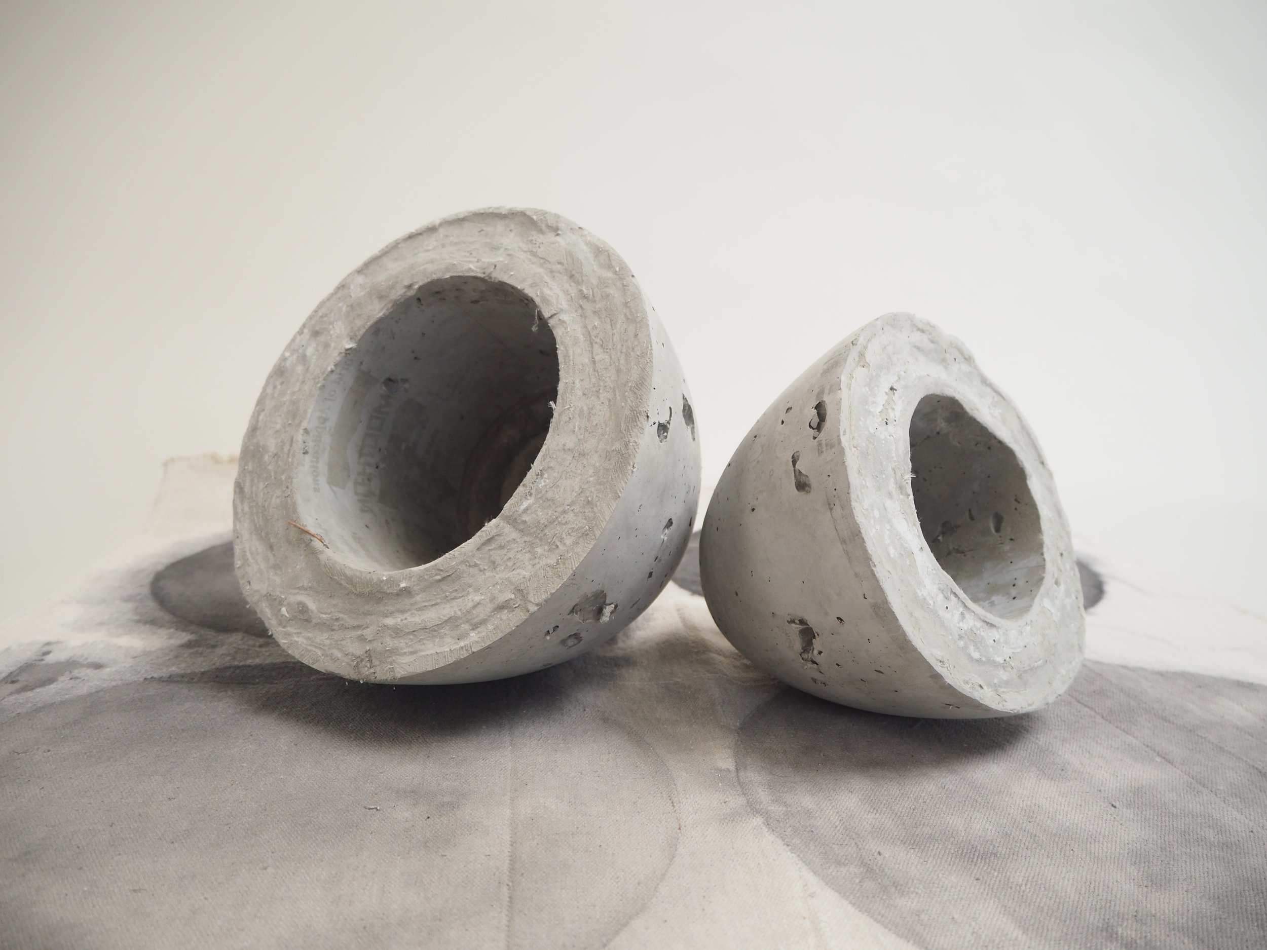 Two vaultic cast concrete vessels by Kept LA shown with custom painted table linen