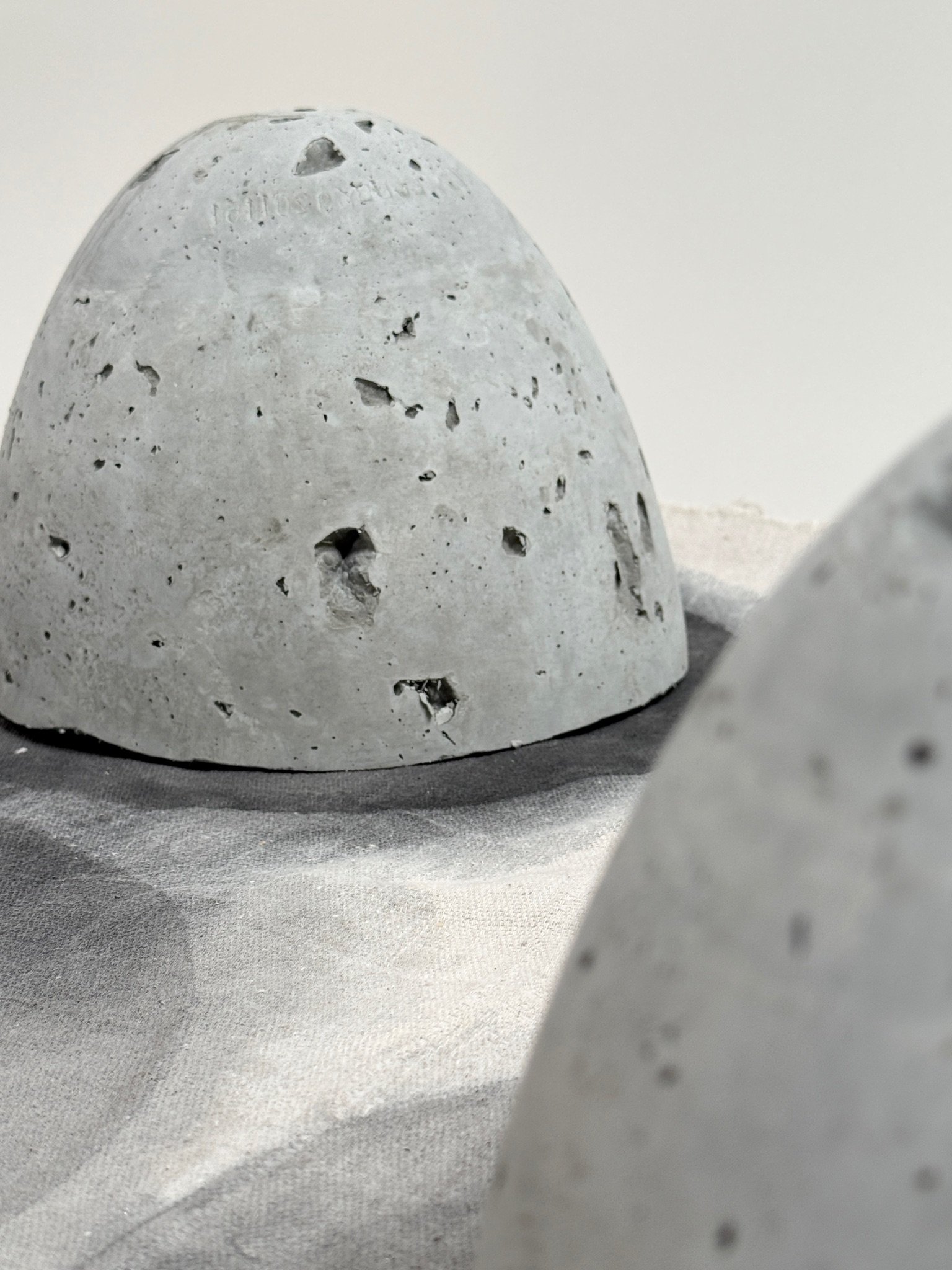 Close detail of inverted Vaultic cement vessel by Kept LA  showing raw pitted concrete surface texture