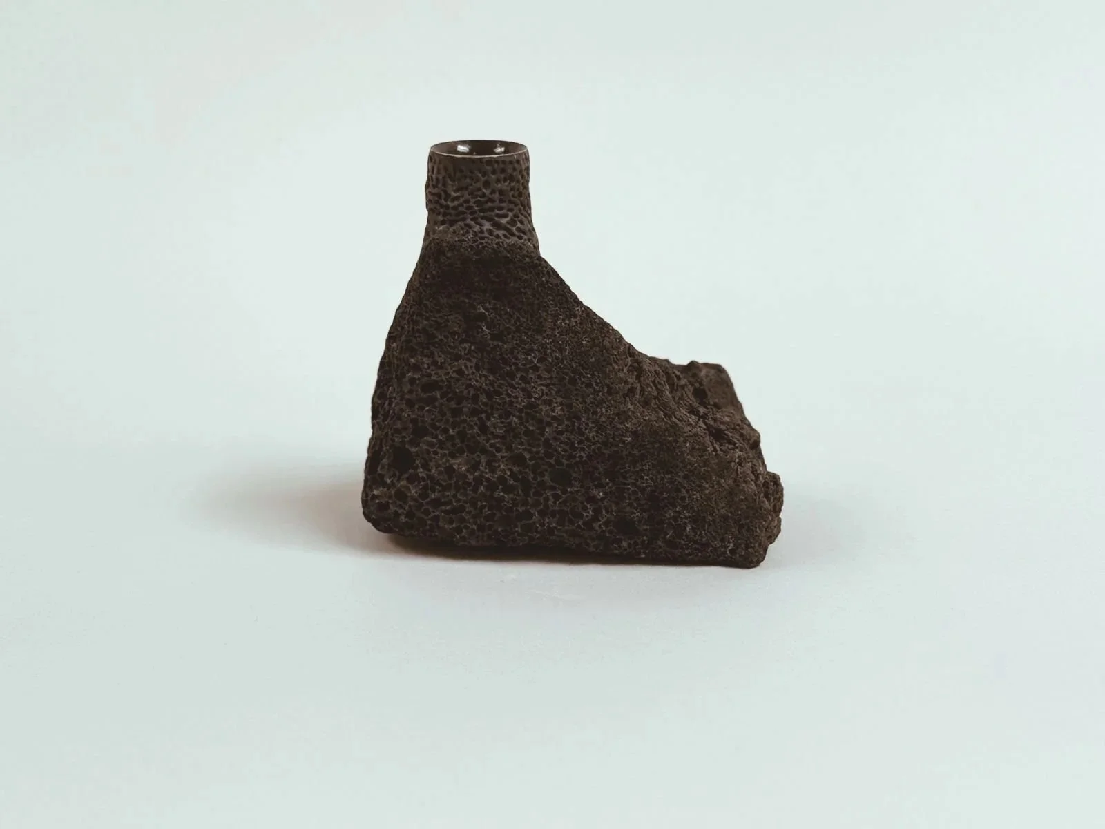 Side product shot of Volcanic Candlestick by Kept LA showing  raw lava stone texture, pitted surface detail and natural  asymmetric silhouette