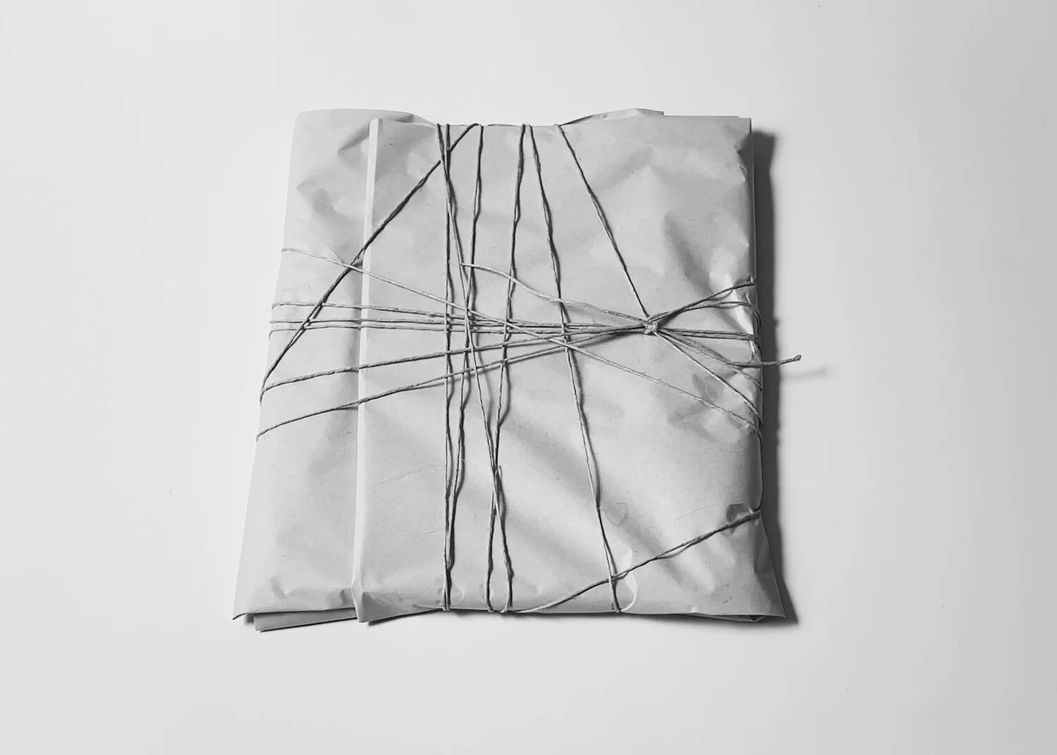 Ritual Letting Go tablet by Kept LA wrapped in newsprint and  bound with wire, showing finished presentation before destruction  ritual, overhead view