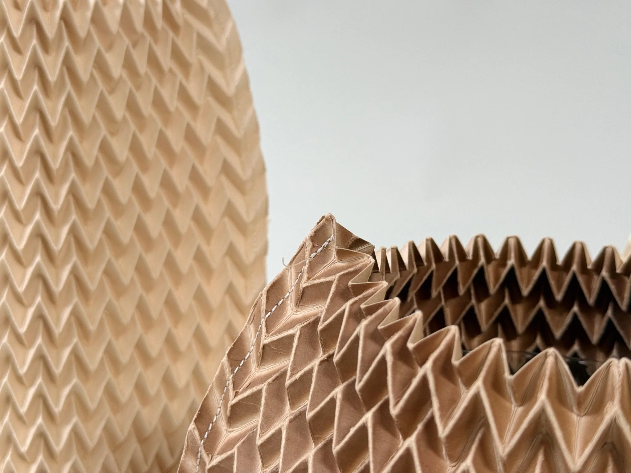 Extreme close detail of Pleated Paper Vase Sleeve by Kept LA  showing chevron pleat pattern and natural variation in tone from  retired fashion pleating forms