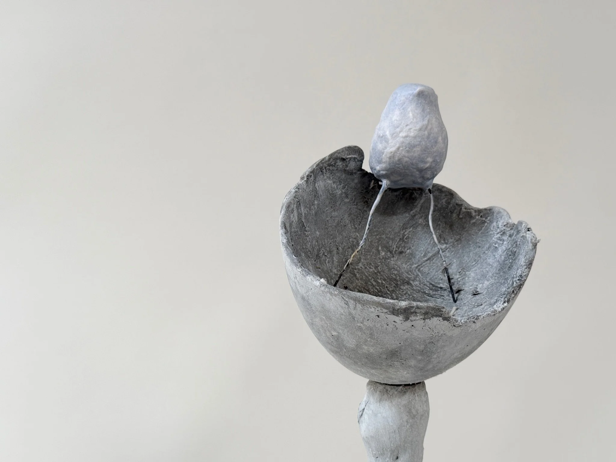 Grey concrete Little Cup Insert by Kept LA with hand-sculpted  plaster bird perched on rim, shown on twisted concrete stem