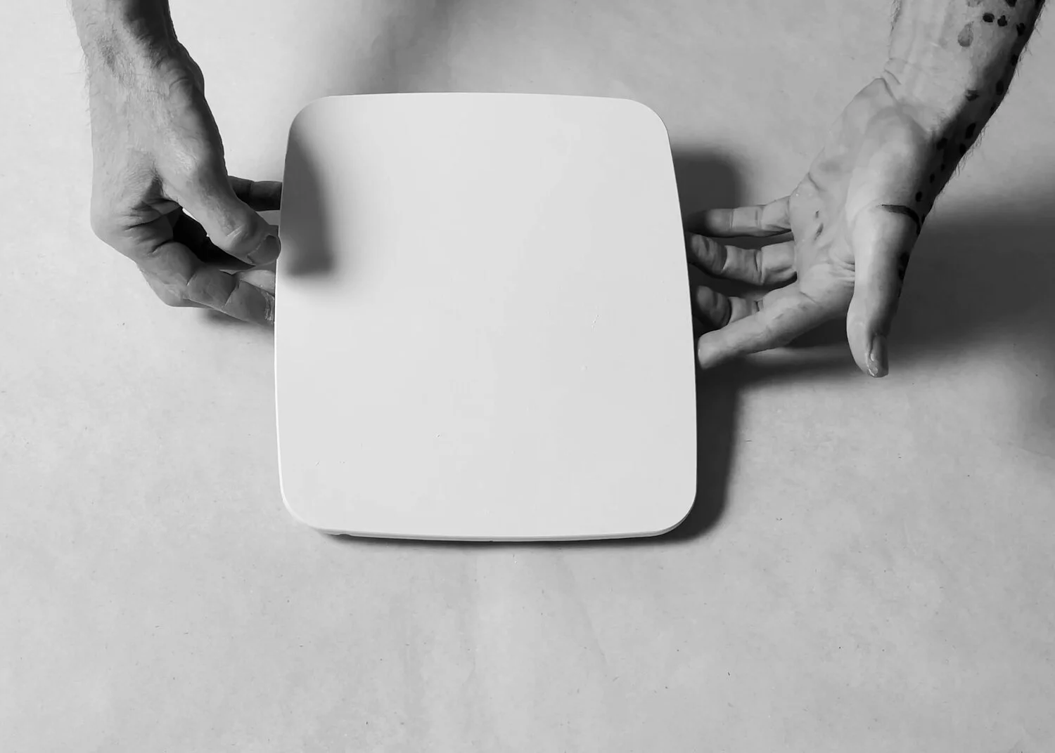 Hands holding unwrapped white plaster tablet from the Ritual  Letting Go collaboration by Kept LA and Swiss artist Thomas  Anthony von Ah, overhead view