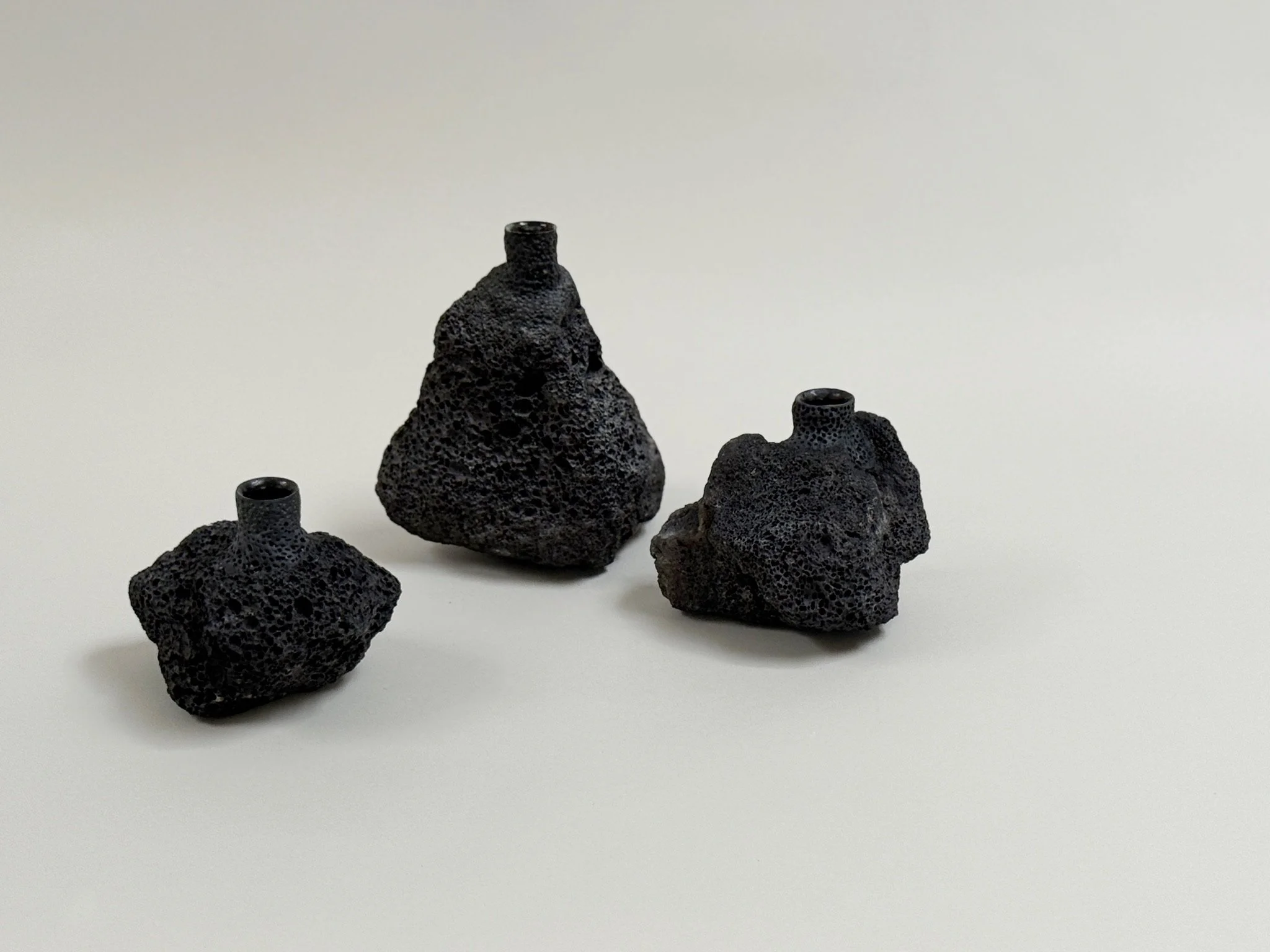 Three Volcanic Candlesticks by Kept LA grouped together showing  range of lava stone forms and varied taper hole sizes, no candles
