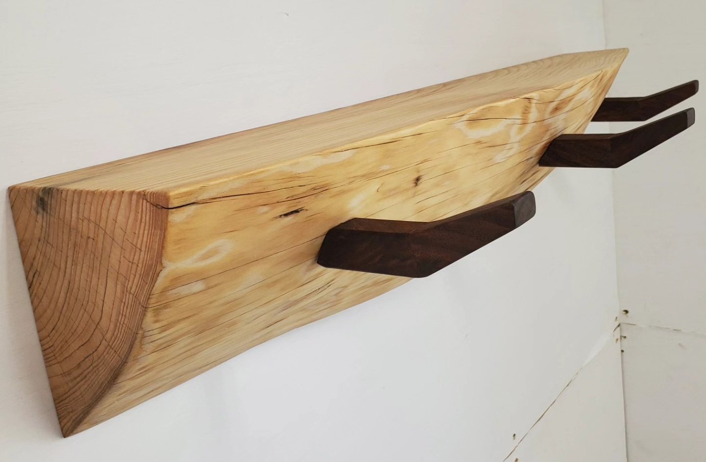 Floating live edge coat rack and shelf.
I originally thought this piece of wood was ash, but after I ran it over the jointer it appears to be maple. Coat hooks are walnut. It mounts on a french cleat so it can be flush to the wall with no visible har