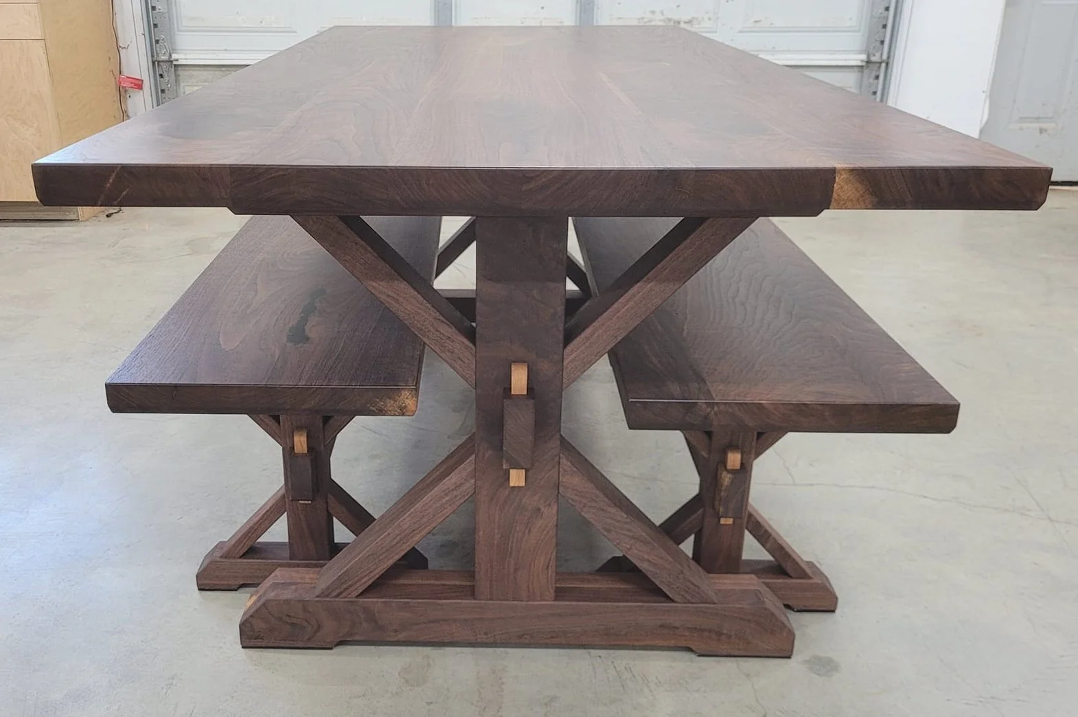 Walnut dining table with two matching benches. The base is all put together with traditional mortise and tenon joinery and through wedged tenons on the stretchers.