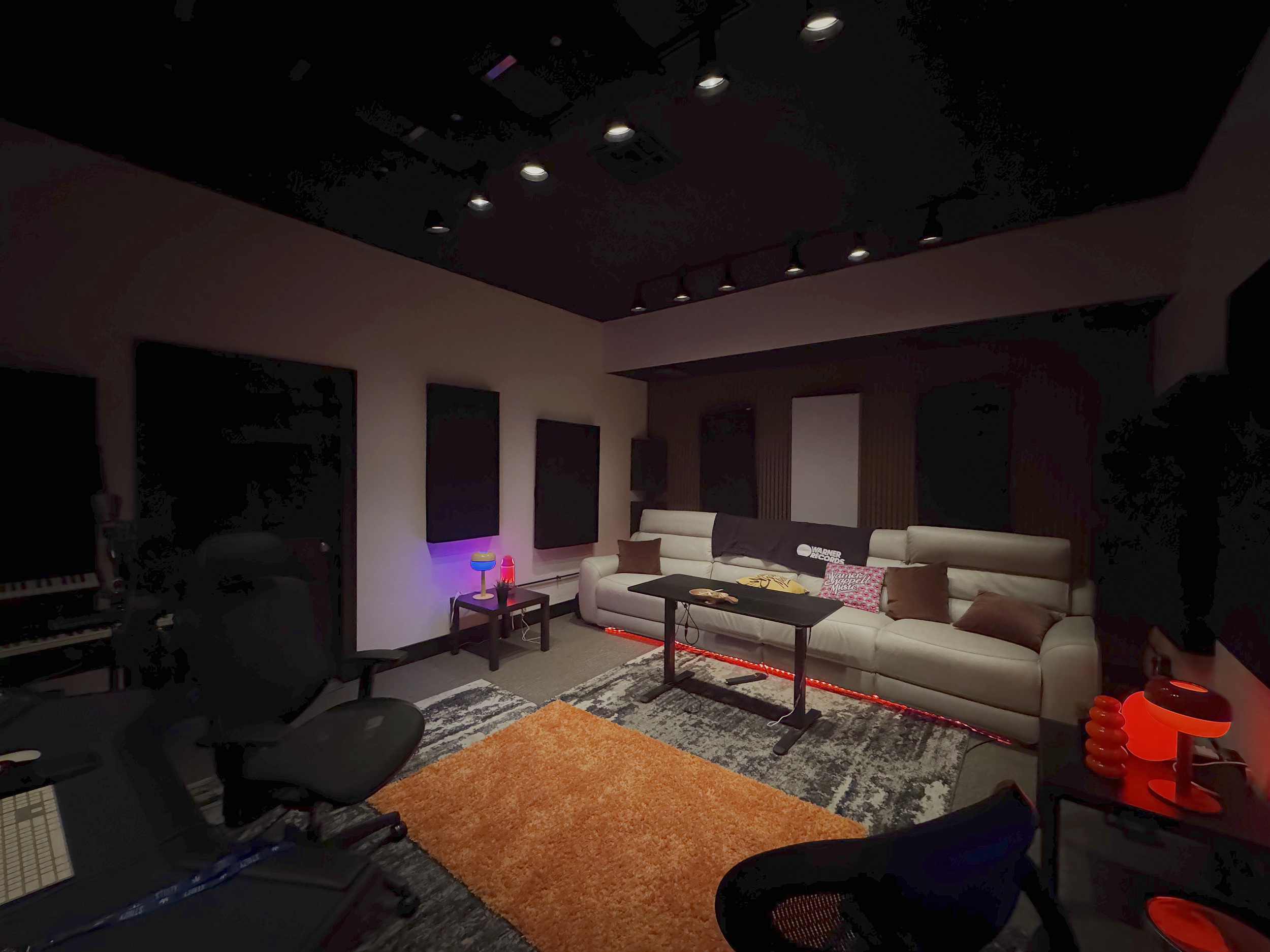 Soundproof recording studio with a white couch, equipment, and decorative lights.