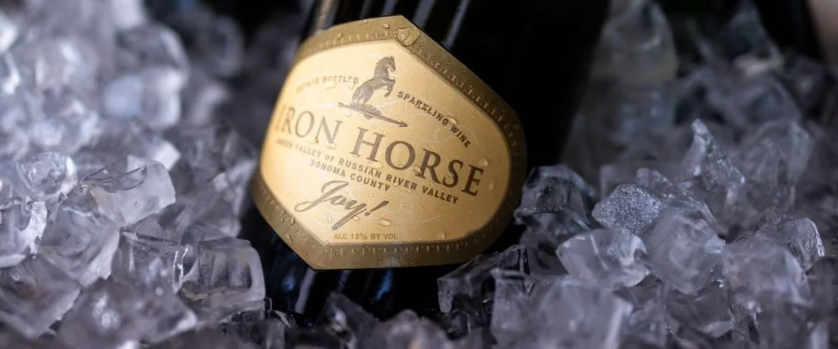 A bottle of Iron Horse sparkling wine resting on ice cubes.