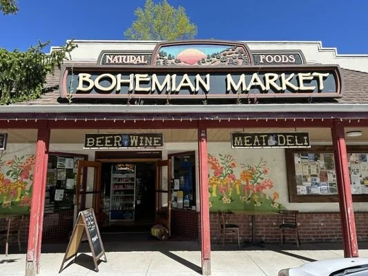 Front of Bohemian Market, a natural foods store with signs for beer, wine, meat, and deli, and colorful mural artwork on the exterior wall.