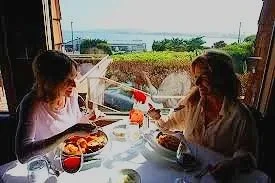 A woman and a girl sitting at a table enjoying a meal together indoors.