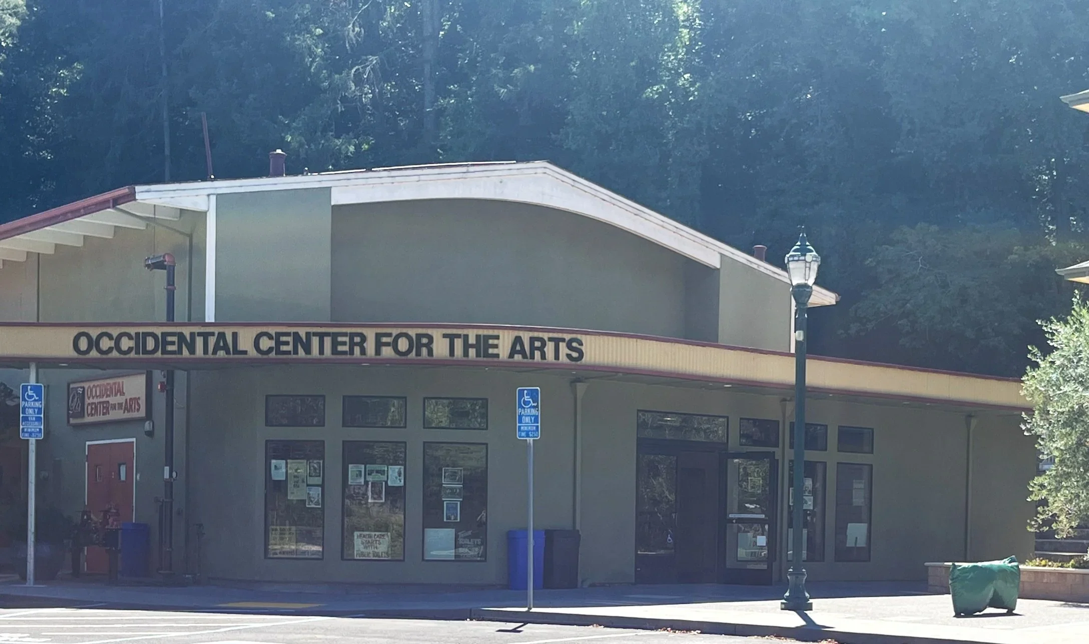 Exterior of the Occidental Center for the Arts building with a the sign on the front and parking signs indicating handicapped parking