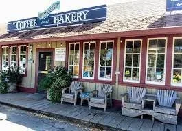 Exterior view of a bakery with a sign for coffee and bakery, and a row of outdoor seating with chairs and tables in front