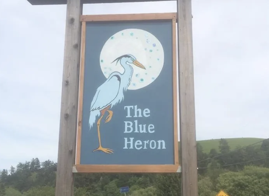 Sign featuring a stylized heron with a large moon in the background, titled "The Blue Heron."