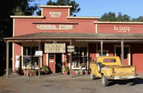 Red general store building with a yellow pickup truck parked in front.