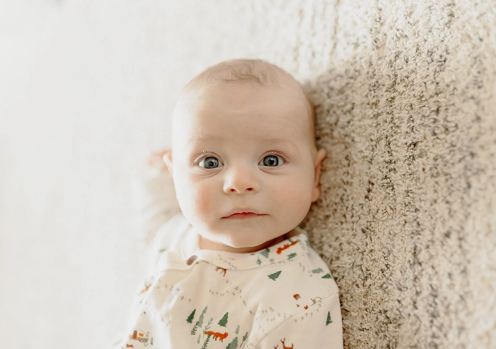 baby laying on floor looking at camera
