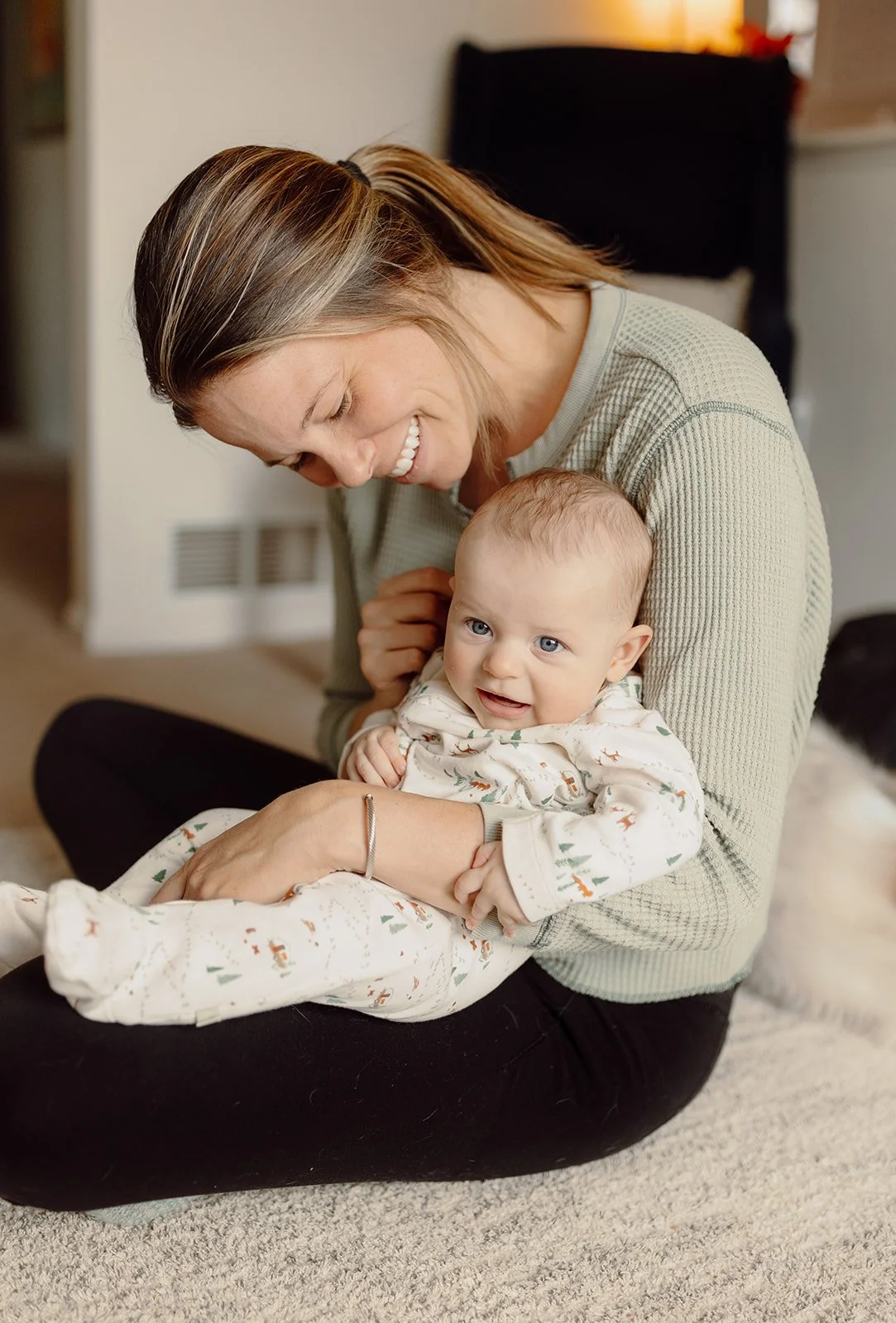 mom holding infant sitting and smiling