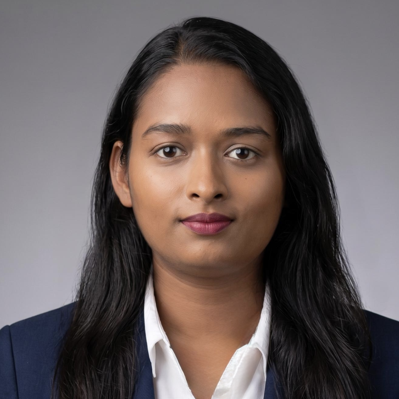 Professional woman with dark hair and wearing a navy blazer and white shirt against a gray background.