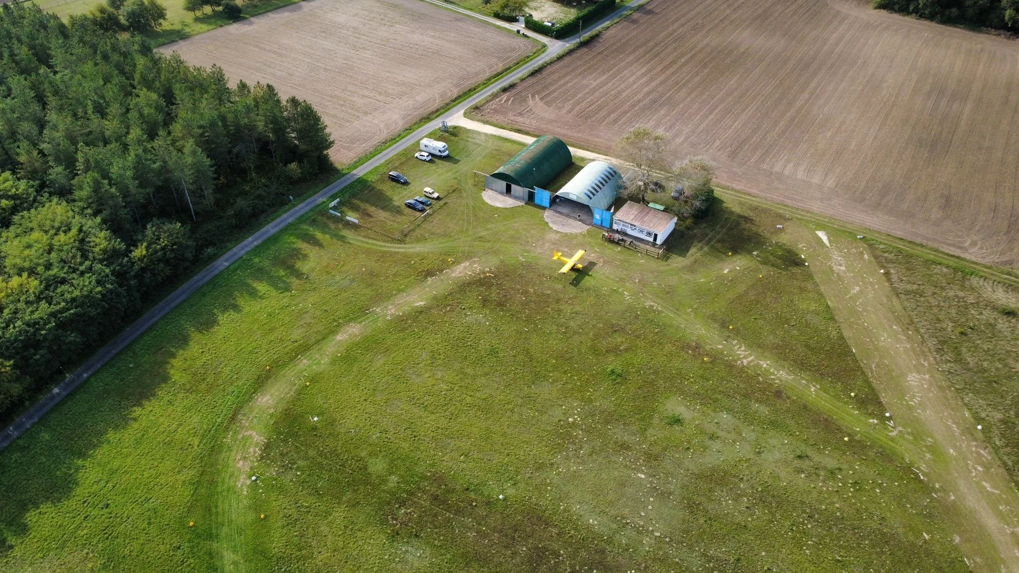 Vue aérienne de la base ULM de Channay-sur-Lathan montrant les hangars et le club house, un des ULM au parking et les alentours.