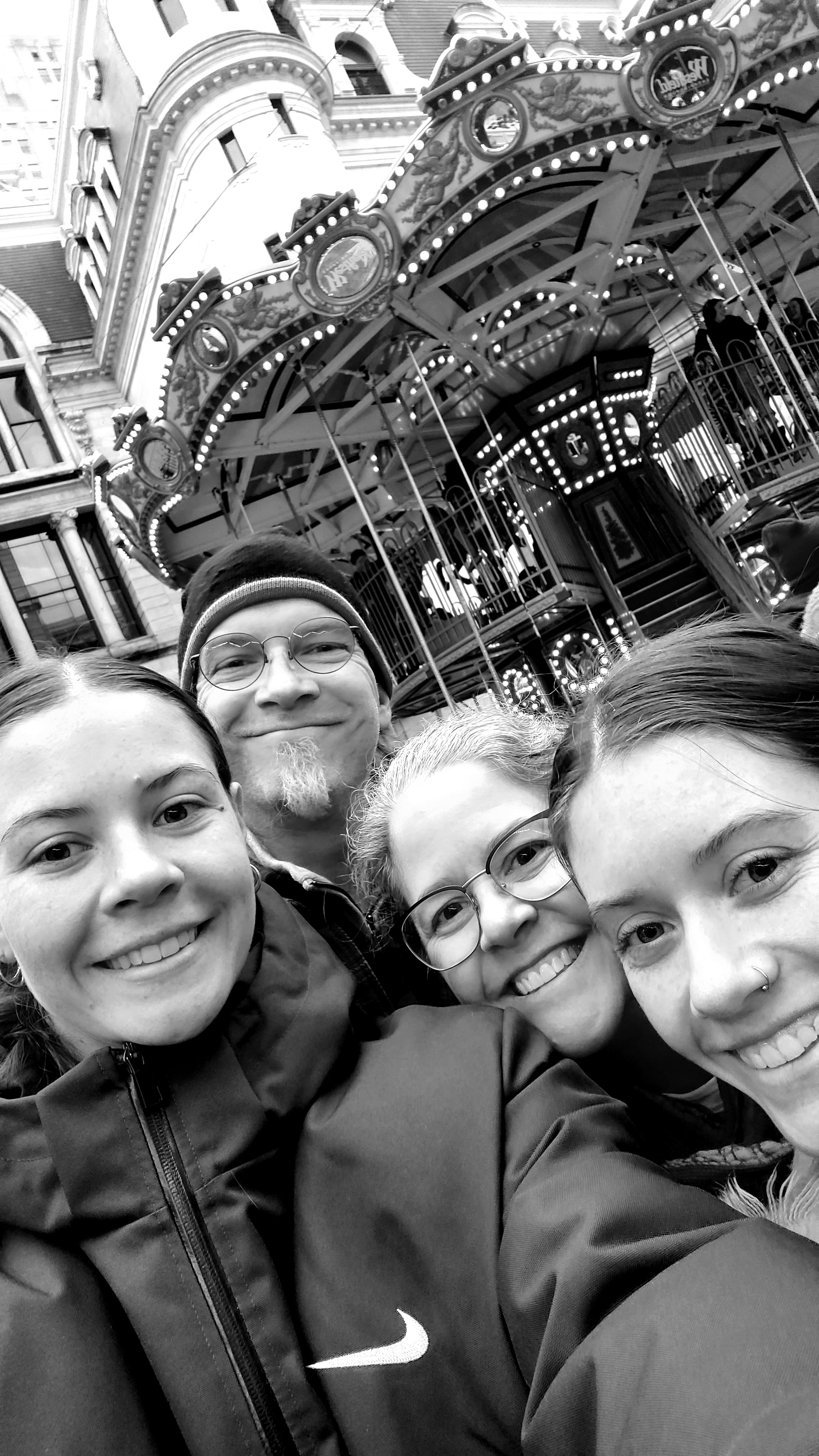 Happy family photo in front of a carousel.