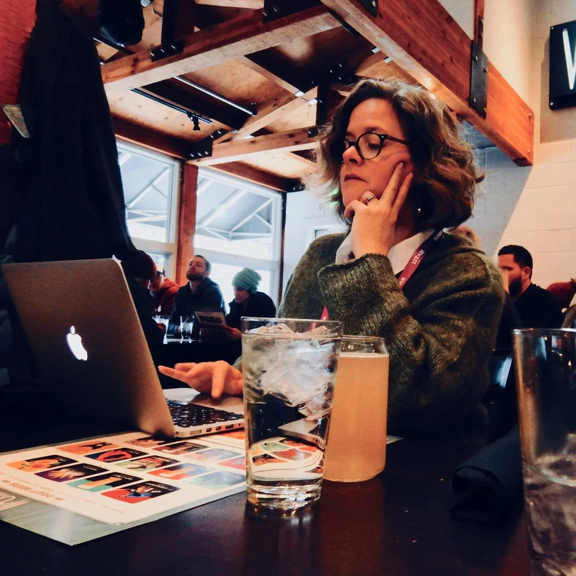 Kerry working, elbow on the table at a restaurant, hand at face while she types on a laptop with the other hand.