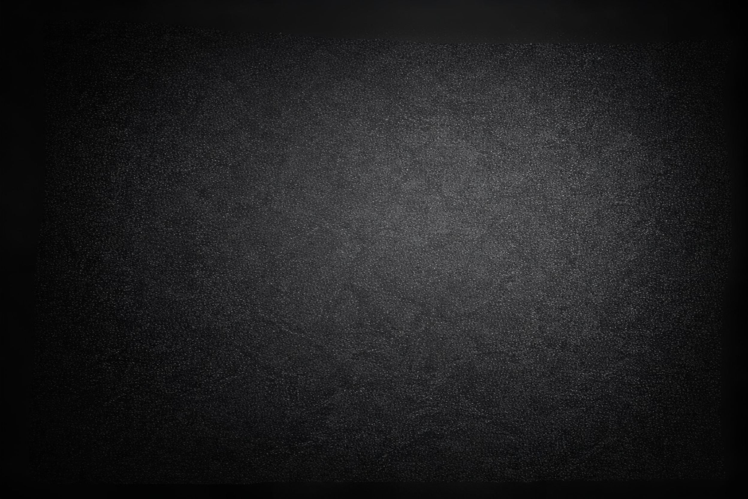 A close-up image of a black, textured surface with specks of light, centered in a dark background.