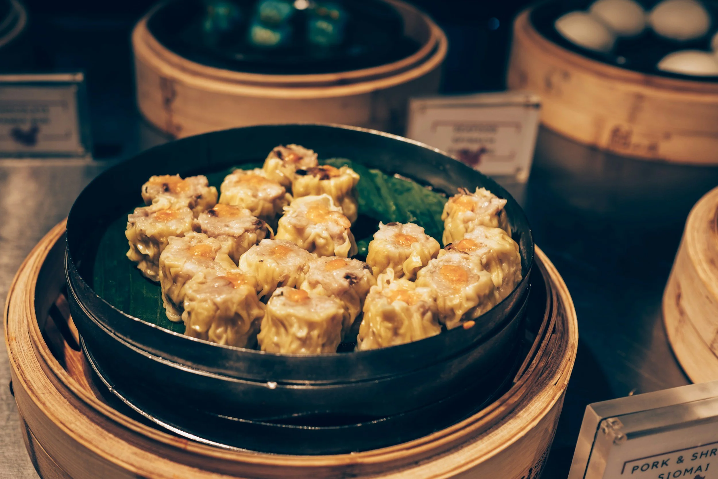Steamed siomai dumplings in a black container on a bamboo steamer tray
