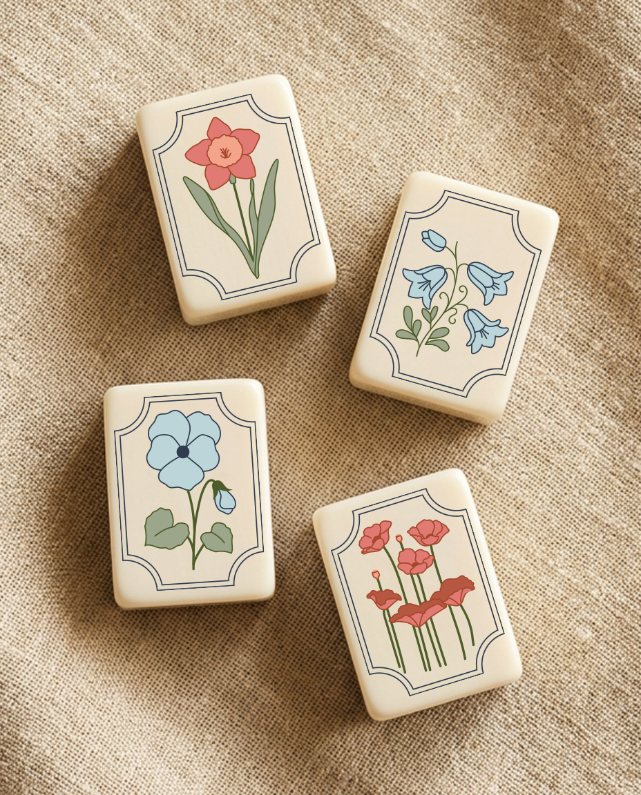 Set of four rectangular boxes with floral designs on a beige fabric surface. Each box features a different flower illustration in pastel colors.