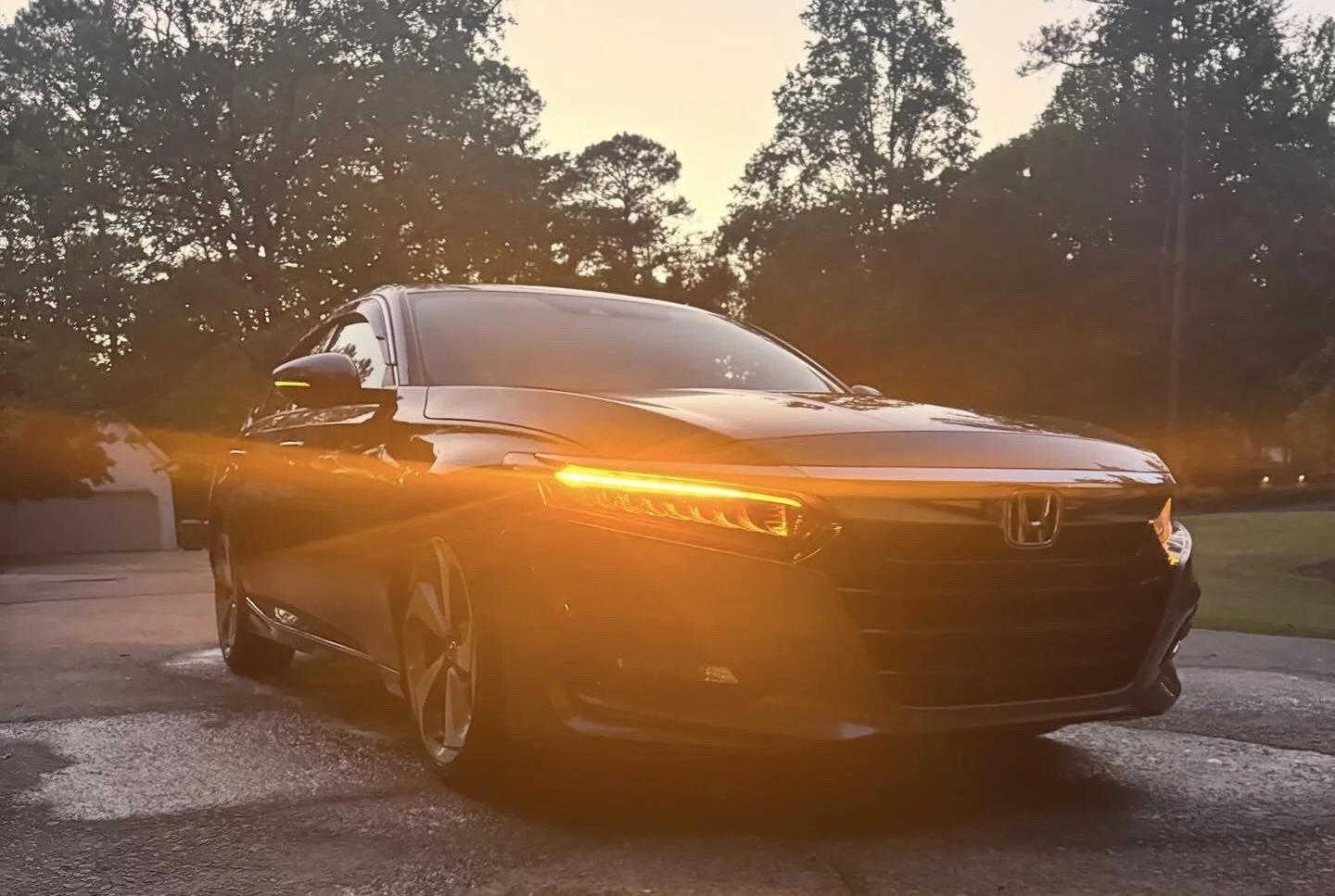 Black Honda sedan parked outdoors during sunset with trees in the background.