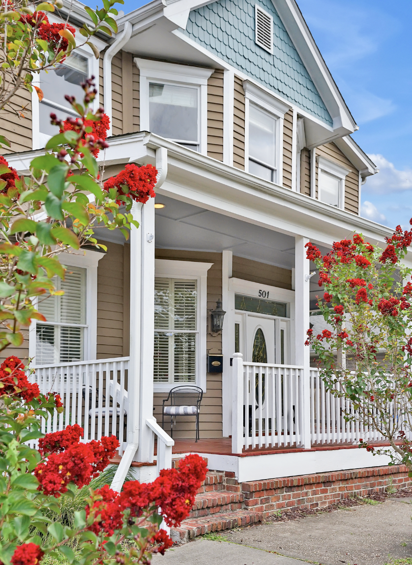 Two-story Victorian-style house in Wilmington, NC, with tan lap siding, a teal gabled upper facade, and a wide covered front porch. You can rent it for a wedding-related event like a wedding weekend, bachelorette party, bridal shower, baby shower, et