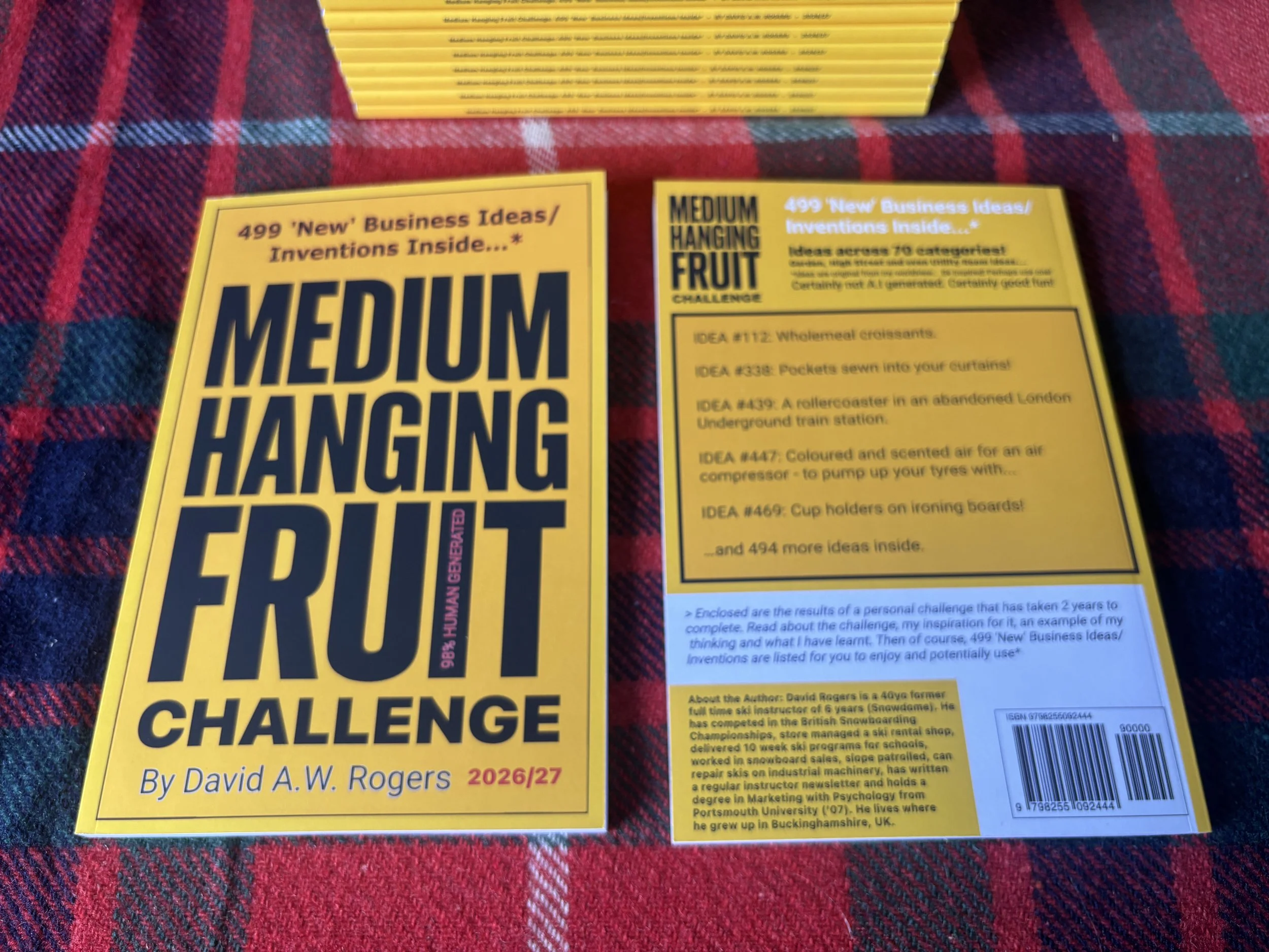 A bright yellow book detailing an account of a challenge to create 499 new business ideas or inventions, authored by David A. W. Rogers for the 2026/27 year.